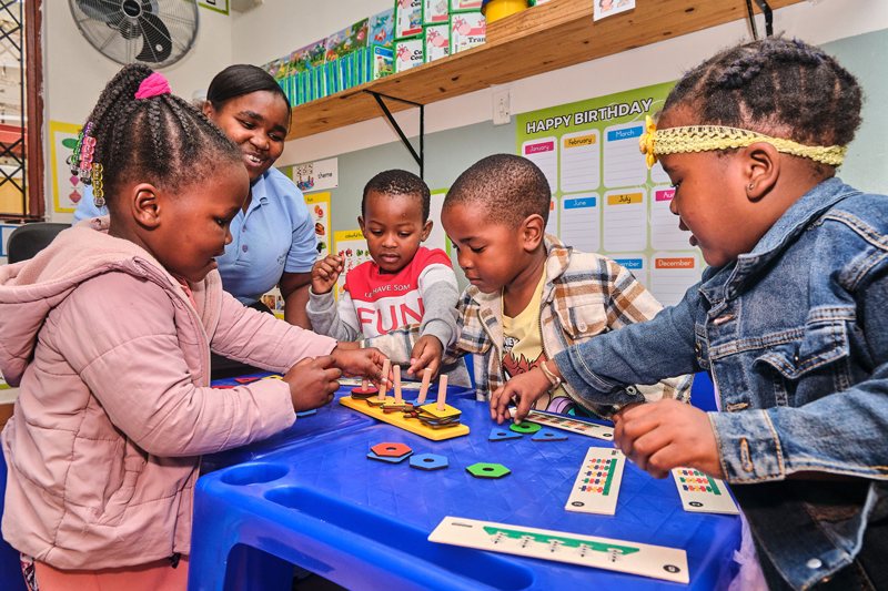 A teacher and young children working with shape puzzles at an early childhood centre